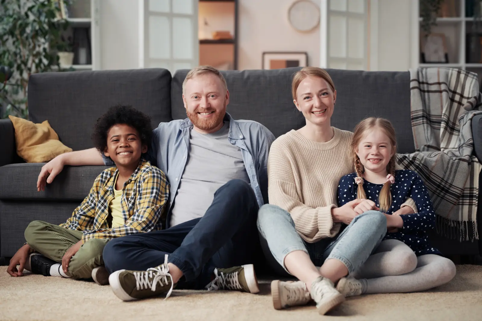 happy-family-with-adopted-children-sitting-on-floor-in-living-room-and-smiling-at-camera